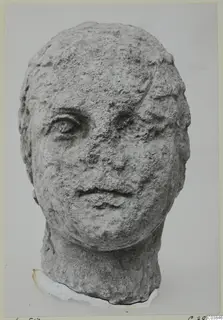 Stone head from Soli, a carved human face with a rough, weathered surface, shown from the front.