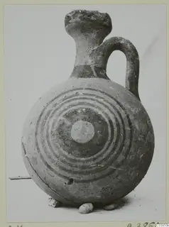 Round jug with concentric painted rings on its body, a tall flaring neck and a loop handle
