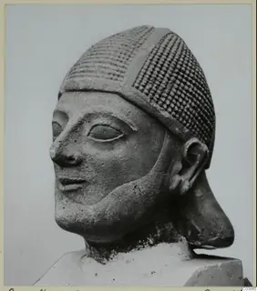 Limestone head sculpture from Amathus wearing a patterned cap, shown in three-quarter view on a block base.