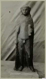 Standing limestone figure of a human figure with a draped cloak, on a rectangular base