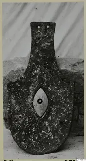 Bronze horse-trappings, a corroded metal plate with a central oval boss and a tang-like upper section.
