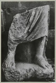 Limestone statue fragment of draped legs and bare feet on a rough base, from Mersinaki