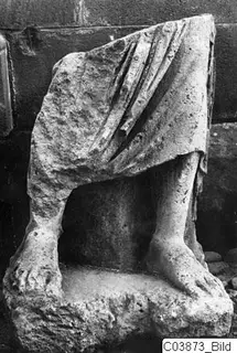 Limestone statue fragment of a draped figure, showing legs and feet on a base, from Mersinaki