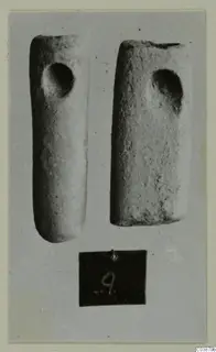 Two cylindrical stone objects, each with a round hole near one end, photographed on grey card with a number label below.