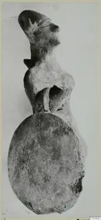 Terracotta figurine of a human figure with a large flat round base, photographed against a pale background