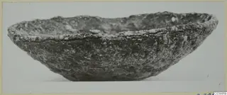 Shallow bowl with a rough, encrusted surface, photographed from the side.