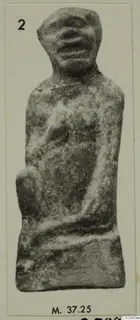 Small terracotta figurine with a broad head and stocky body, shown on a pale card mount
