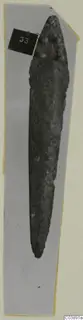 Bronze tool from Lapithos Tomb 322 E, long and pointed, photographed on grey card with a number label.