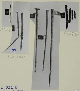 Photo mount of corroded metal rods, nail-like pieces and dark fragments from Lapithos Tomb 322 E
