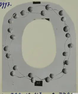 Necklace of rounded beads strung on fine thread, laid out on a grey card mount