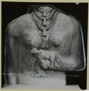 Limestone sculpture fragment of a figure's upper body, with a bead necklace and a small carved animal at the chest