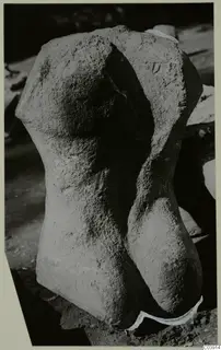 Limestone statue torso from Vouni, headless and armless, photographed outdoors on rough ground.