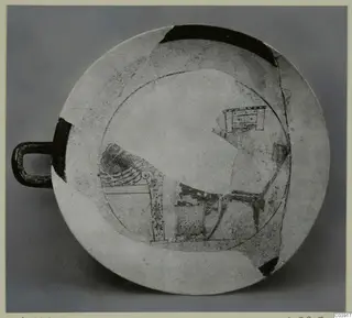 Shallow pottery dish with a loop handle and dark painted motifs, reconstructed from fragments