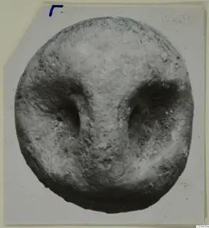 Terracotta face-like object from Vouni, seen straight on, with deep eye hollows and a raised nose ridge