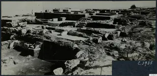 Excavated ruins at Vouni palace: low stone walls, paved floors and steps, with the sea at the left edge.