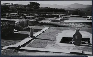 Stone steps, a column and a large vessel-like object among ruins at the palace at Vouni, with hills beyond