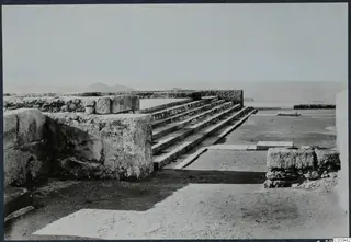 Stone steps and low walls among ruins at the palace at Vouni, with hills and sea on the horizon.