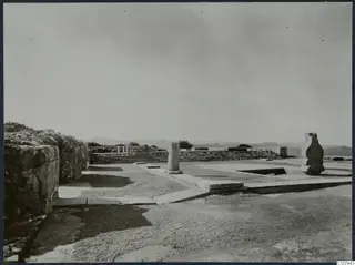 Ruined stone walls, a flight of steps and a column drum at Vouni Palace, with hills behind.