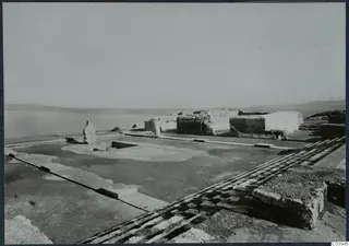Excavated ruins at Vouni Palace: a stone wall, a paved floor with a checkered band, and steps at the right