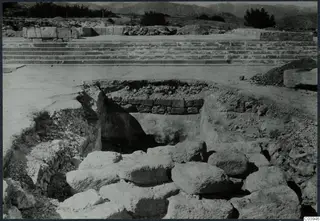 Excavation at Vouni showing large fallen stones in a trench, with a broad stone staircase behind.