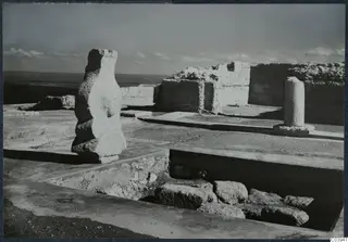Excavation at Vouni Palace showing a tall stone block, a column base, ruined walls and a trench full of fallen stones