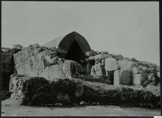 Large stone blocks and a canvas tent over an arched opening at the palace at Vouni