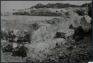Excavated stone walls and stepped masonry at Vouni, with low rubble walls and a hillside behind.