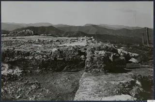 Vouni Temple of Athena: rough stone foundations on a hilltop, with a fence and hills stretching into the distance.