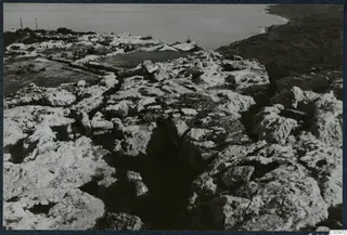 Stone ruins at Vouni with a water-filled channel between blocks and the sea beyond
