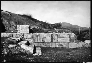 Excavated ashlar stone wall and steps at the theatre at Soli, with a wire fence on the hillside