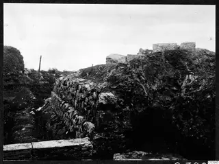Excavated stone wall and cut blocks at Soli: the theatre, with a wire fence and posts behind