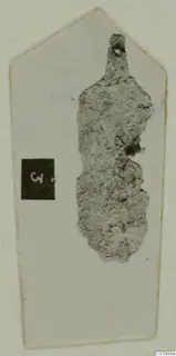 Corroded metal object from Lapithos Tomb 322B, with a small hole near its narrow upper end