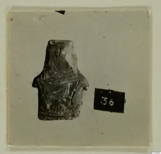 Idol fragment from Lapithos Tomb 322 B, photographed on a card beside a number label.