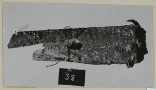 Corroded bronze tool fragment from Lapithos, Vrysi tou Barba tombs, shown with a number label