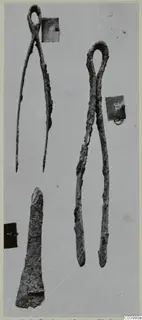 Two iron tongs and a tapered iron fragment laid out on a pale grey surface