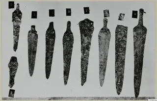 Bronze blades and tools from Lapithos Tomb 322A, laid out in a row with number labels