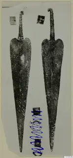 Two long metal weapon blades with curled tangs, from the Lapithos finds
