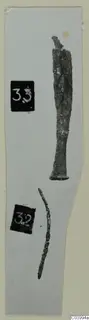 Two corroded metal tools on a grey card strip: one long with a flared base, a thin curved fragment below, beside number labels.