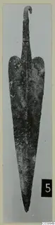 Corroded metal blade with a hooked tang, find from the Vrysi tou Barba tombs at Lapithos