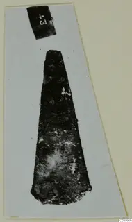 Corroded metal tapering object from Lapithos Tomb 313, mounted on a card with a number label