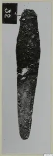 Corroded bronze tool from Lapithos Tomb 322 D, photographed upright against a pale background