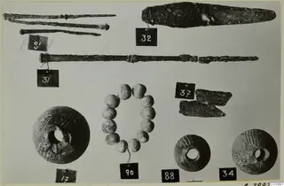 Bronze tools, rods, a blade and beads from Lapithos Tomb 322 D, laid out with numbered tags