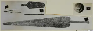 Bronze tools and weapons from Lapithos Tomb 323 D: a long blade, a short tanged implement, tweezers and a pin laid out on a card.