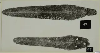 Two corroded bronze blades from the Vrysi tou Barba tombs at Lapithos, with number labels 42 and 47.