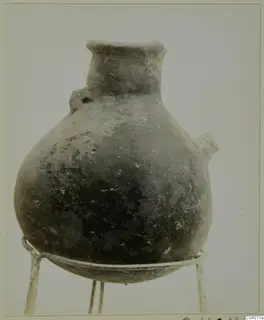 Pottery Red Polished III jug from the Vrysi tou Barba tombs at Lapithos, standing on a wire stand.