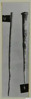 Two bronze tools photographed upright, one long and thin, the other with a flared head and a pointed end