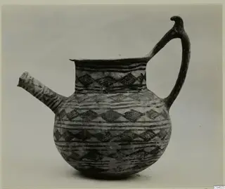 Jug with a long spout and a handle ending in a bird-like head, decorated with dark bands and lozenges
