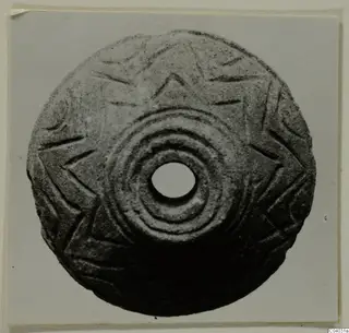 Round stone disc with a central hole, concentric rings and an incised star-like pattern, from Idalion