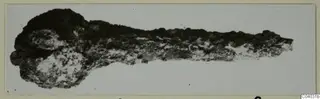 Corroded metal object from Idalion, Tomb 3, lying horizontally against a pale background