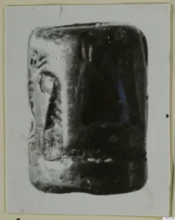 Stone seal with an engraved design on one side, photographed on a light card mount